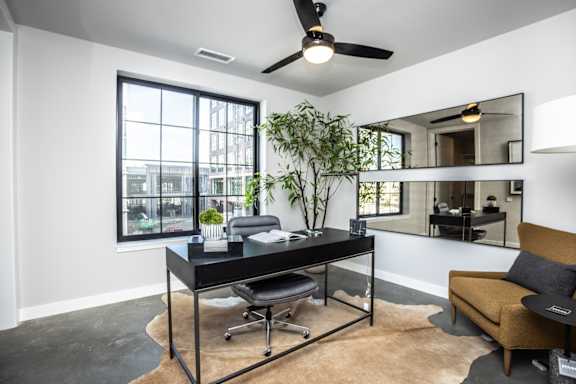 A room with a desk, chair, and a mirror on the wall.