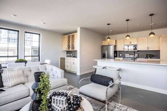 A modern living room with a grey sofa, a white armchair, and a coffee table with decorative items.