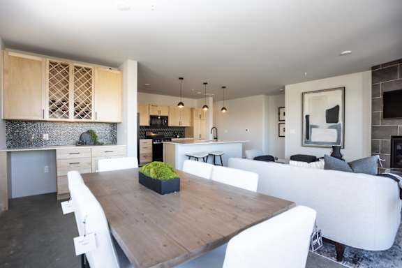 A modern dining room with a wooden table and white chairs.