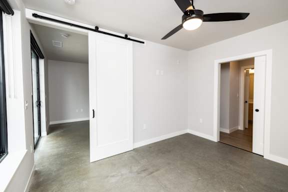 A room with a ceiling fan and sliding doors.