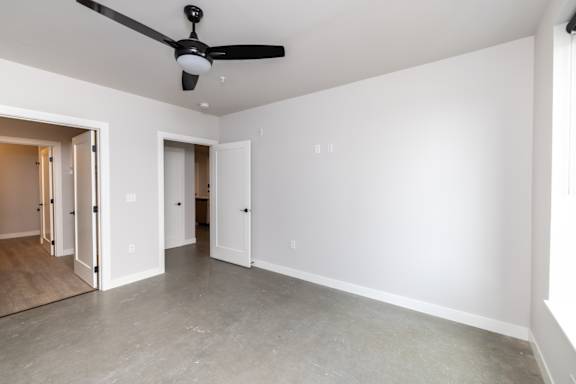 A room with a ceiling fan and two doors.