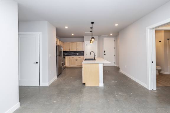 A kitchen with a white door and a countertop with a sink.
