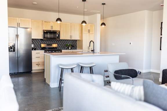 A modern kitchen with a white island and a grey sofa.