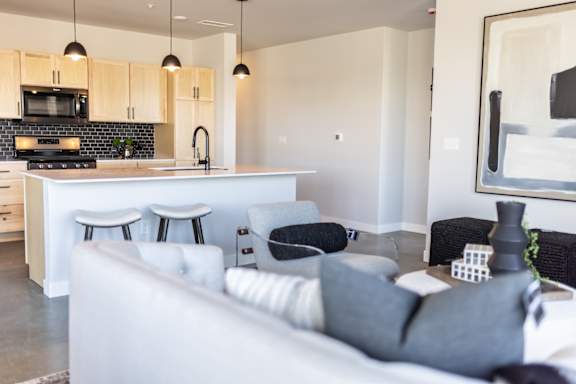 A modern living room with a white couch and a kitchen area in the background.