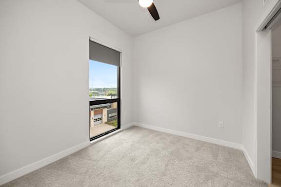 A room with a carpeted floor and a ceiling fan.
