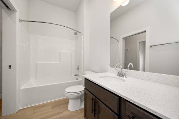 A white bathroom with a toilet, sink, and shower.