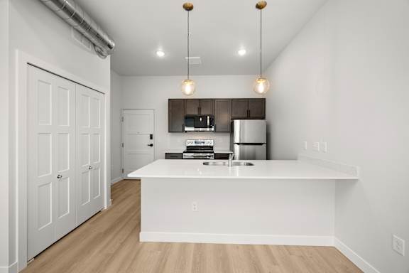 A kitchen with white cabinets and a white island with a sink.