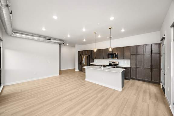 A modern kitchen with wooden floors and a white island.