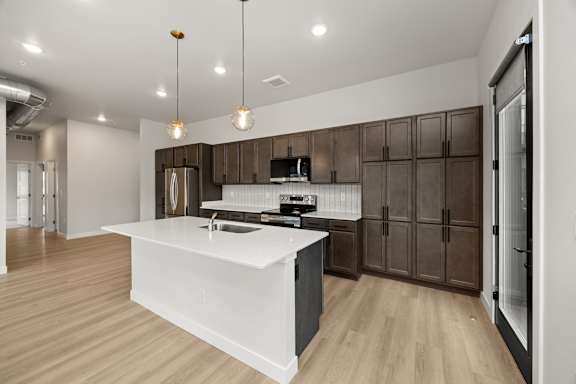 A modern kitchen with a white island and wooden cabinets.