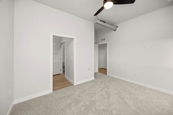A room with a carpeted floor and a ceiling fan.