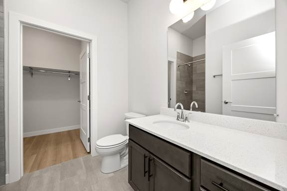 A bathroom with a toilet, sink, and mirror.