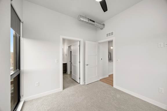 A room with a carpet floor and a ceiling fan.