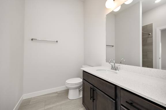 A white toilet sits in a bathroom with a white sink and a mirror.