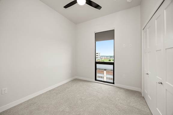 A room with a window and a ceiling fan.