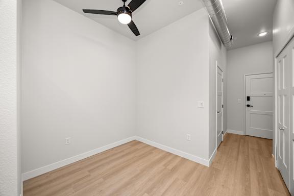 A room with a ceiling fan and wooden flooring.