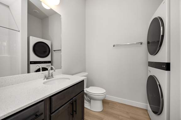 A white toilet sits next to a washer and dryer in a small bathroom.