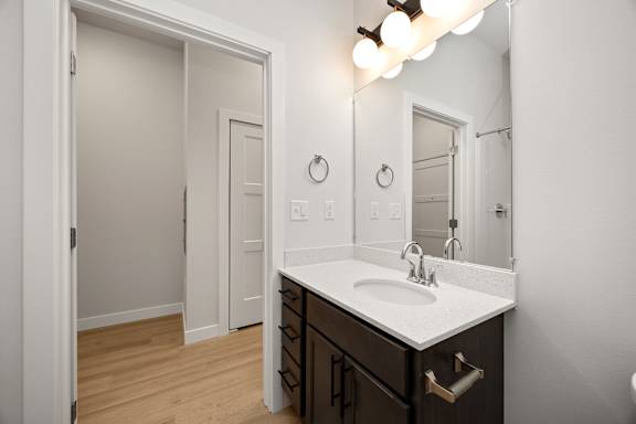 A bathroom with a sink, mirror, and lighting fixture.