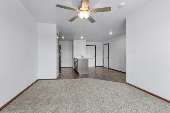 A room with a ceiling fan and a carpeted floor.