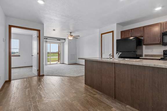 A kitchen with brown cabinets and a black fridge.