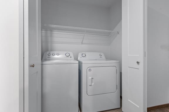 Two white front loading washing machines in a small laundry room.