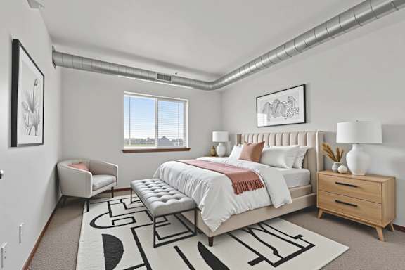 A bedroom with a large bed, a bench, and a rug with a black and white design.