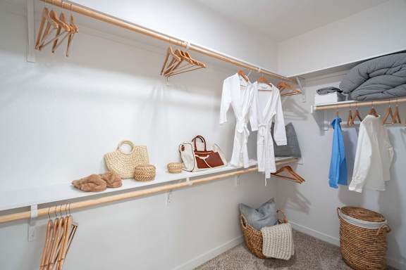 A white closet with clothes and bags on shelves.