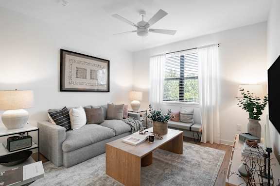 A living room with a grey couch, a coffee table, and a ceiling fan.