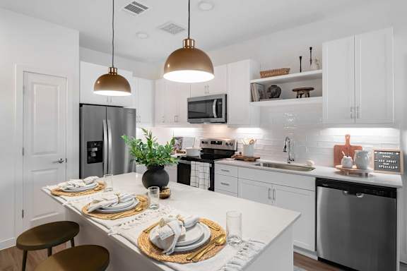 A modern kitchen with a dining table set for two.