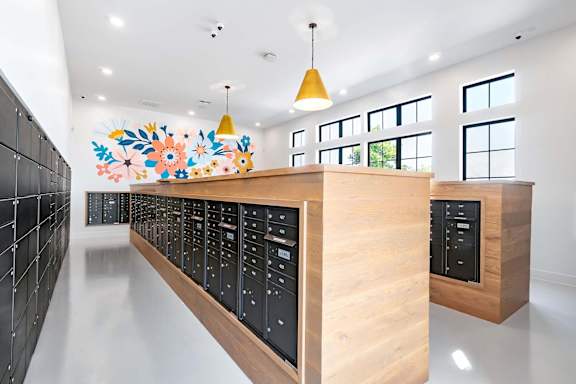 A long hallway with a black tile wall and a wooden counter with a colorful mural above it.