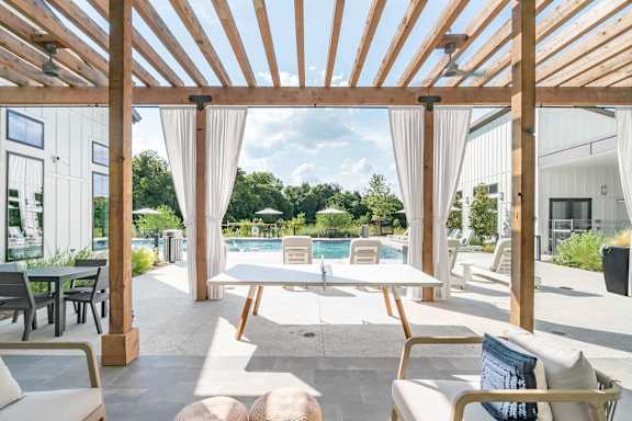 A wooden pergola over a patio with a table and chairs.