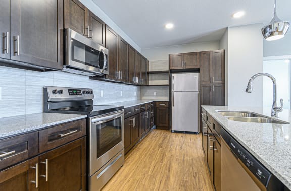 a kitchen with wooden cabinets and stainless steel appliances at The Fitzroy San Marcos, San Marcos, TX