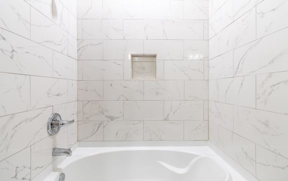 a white tiled bathroom with a tub and a sink at The Fitzroy San Marcos, San Marcos, Texas