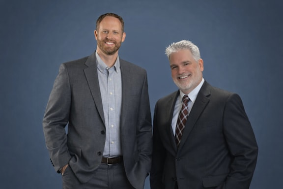 Three people in business attire stand side by side.