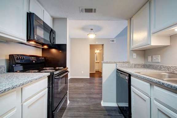 A kitchen with black appliances and white cabinets.