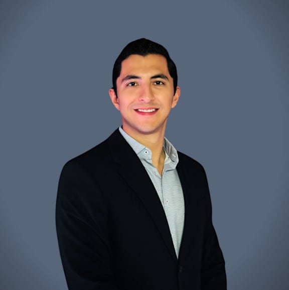 A man in a black suit and light blue shirt.