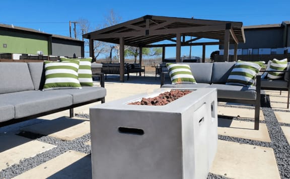 a concrete fire pit with pillows and couches in front of a pavilion at Ivy Plains at Brooks Apartments, San Antonio , TX, 78223