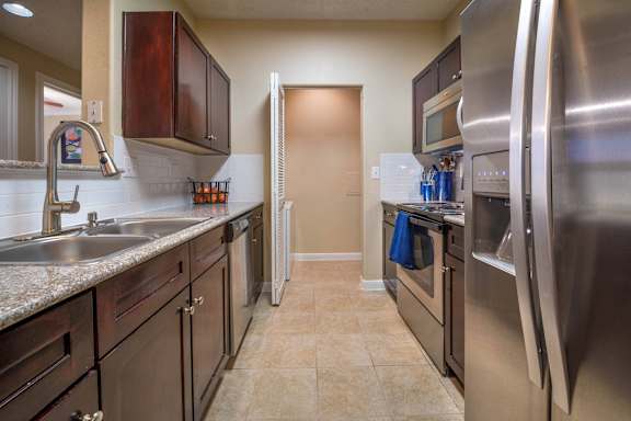 A kitchen with a sink, stove, and refrigerator.