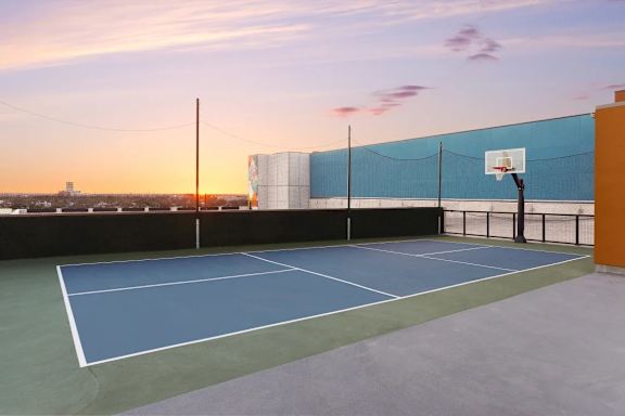 Rooftop sports court with basketball hoop at sunset at THE'68 Apartments, San Antonio, TX 78205
