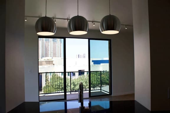 Dining area with pendant lighting and balcony view at THE'68 Apartments, San Antonio, Texas