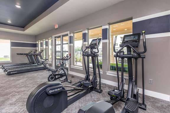 A row of treadmills and elliptical machines in a gym.