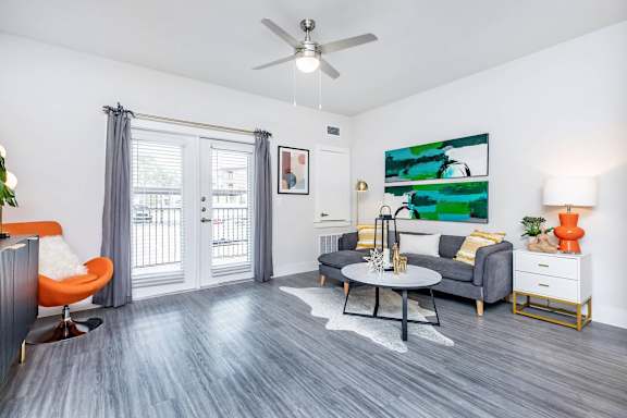 A living room with a grey couch, orange chair, and a painting on the wall.