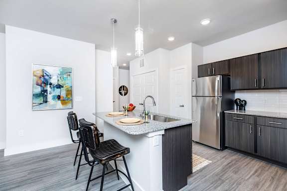 A kitchen with a white counter top and a black chair.