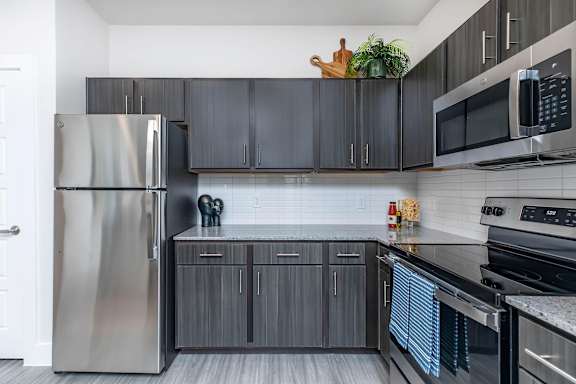 A modern kitchen with a stainless steel refrigerator and black cabinets.