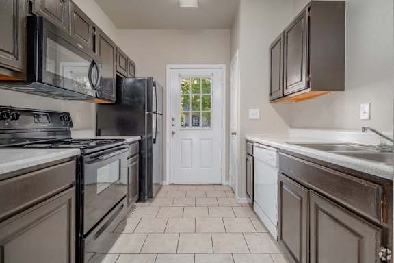 A kitchen with dark brown cabinets and a white door.