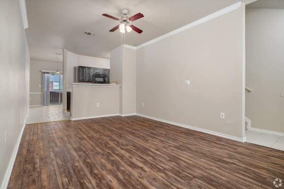 A room with a ceiling fan and wooden flooring.