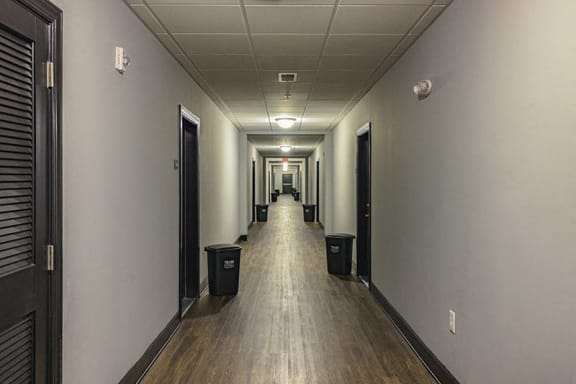 a hallway with a wooden floor and a row of doors