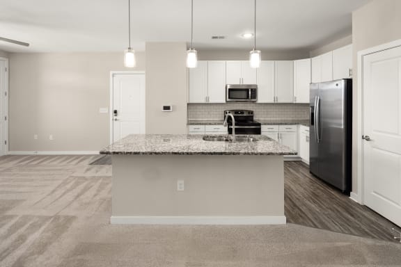a kitchen with a granite counter top and stainless steel refrigerator at Abberly Liberty Crossing Apartment Homes, Charlotte, NC
