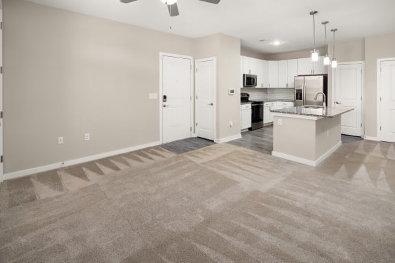 an empty living room with a kitchen with a sink and refrigeratorat Abberly Liberty Crossing Apartment Homes, Charlotte