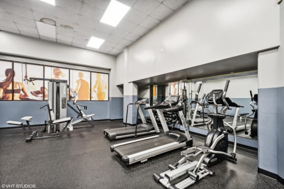 a gym with treadmills and other exercise equipment in a building with windows at Delmar Loop Apartments, St. Louis, MO, 63112
