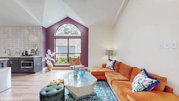 A modern living room with a large window and a kitchen area.